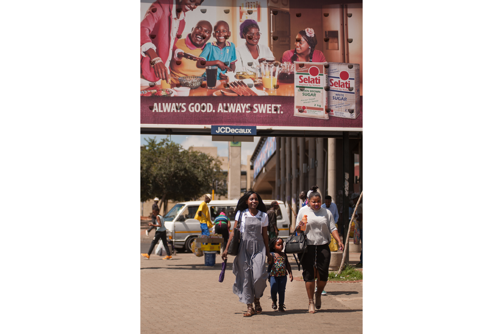 Soweto. De compras por el barrio. La publicidad a menudo transmite mensajes que encajan a duras penas con el decorado